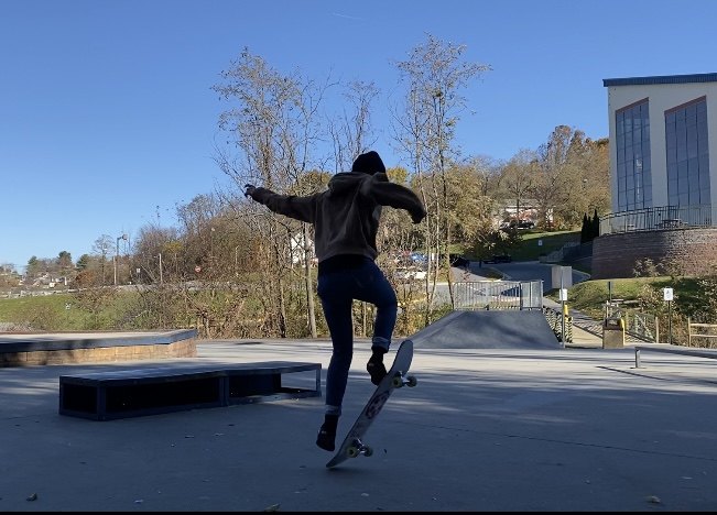 Madeline riding a skateboard off a ledge at a skatepark