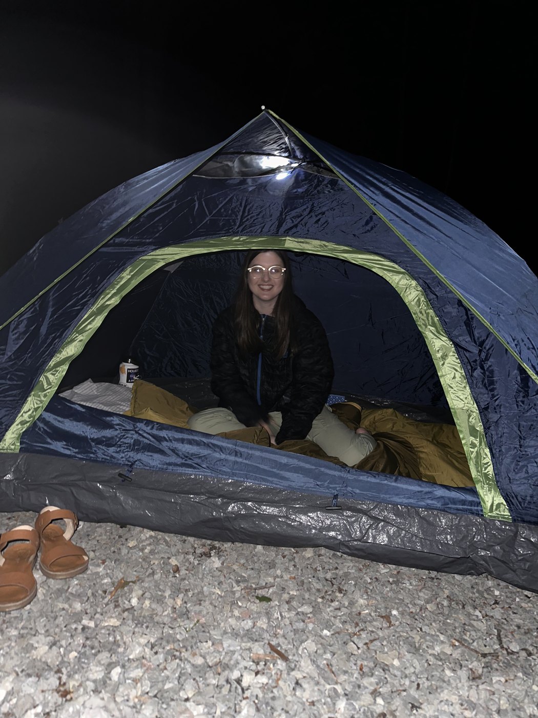 A lit tent at night with someone sitting inside