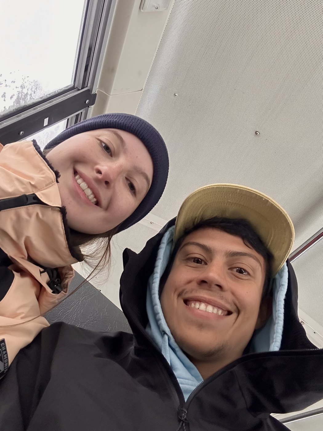 Two friends bundled in hats and coats smiling at the camera