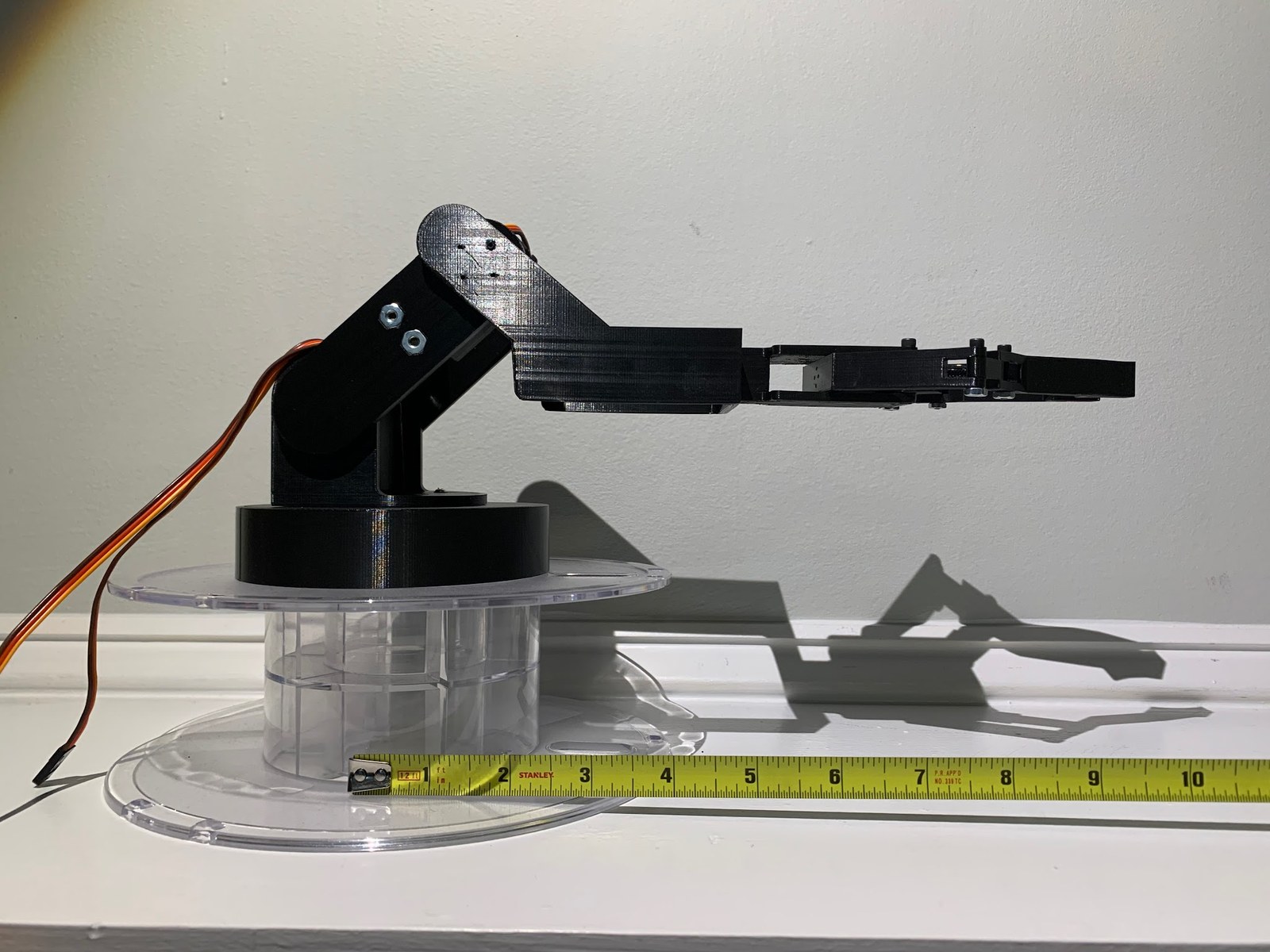 The finished 3D-printed arm on its spool base, measured against a tape