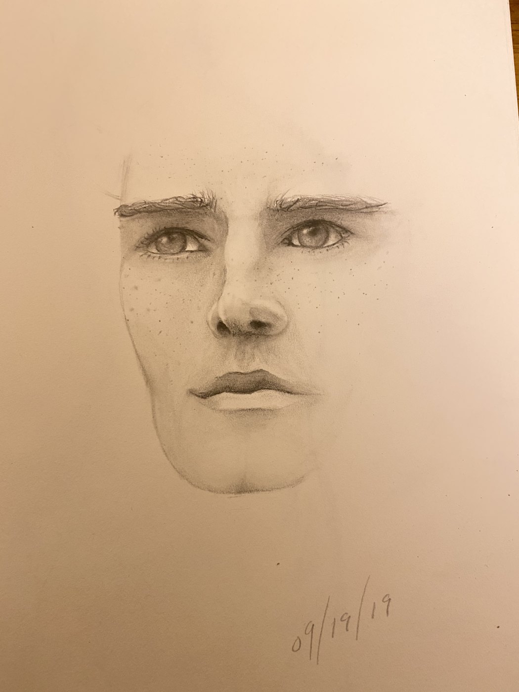 Graphite portrait drawing of a face looking straight ahead