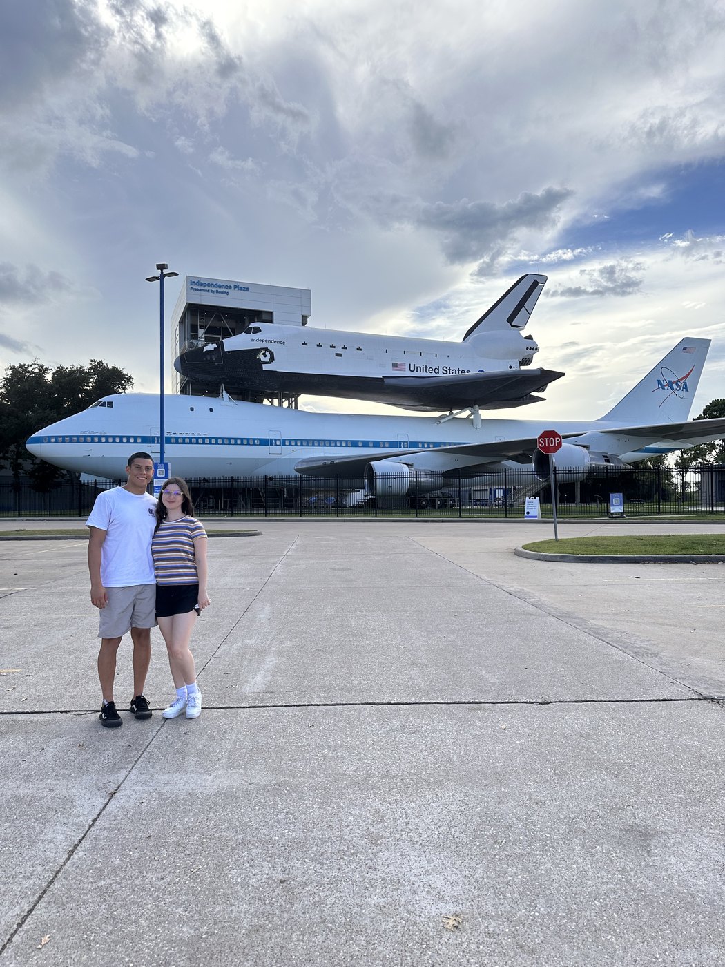 Madeline and a friend in front of the Shuttle Carrier Aircraft under a bright cloudy sky